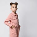 Portrait of a cute girl in a casual cotton jumpsuit with pockets, standing half-turned to the camera, hands in pockets Royalty Free Stock Photo