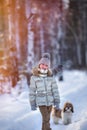 Portrait of a cute girl on a cold day in the forest at sunset. Dog in the background Royalty Free Stock Photo