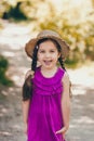 Portrait of cute girl dressed in bright standing in the forest road