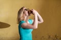 Portrait of a cute girl in a green dress walking outside and eating a burger on a warm summer day. Beautiful blonde in sunglasses