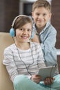 Portrait of cute girl listening music on digital tablet while brother standing behind her Royalty Free Stock Photo