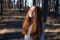 Portrait of cute girl with long bright red hair in the park