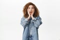 Portrait of cute girl reacts to surprise, looks amazed and shocked, say wow, stands impressed against white background