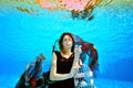 Portrait of a cute girl with red hair, who poses at the bottom of the pool in a red dress and with a red cloth in her