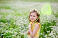 Portrait of a cute girl in a yellow T-shirt with a floral daisy wreath on her head. A child stands in a field of chamomiles with a Royalty Free Stock Photo