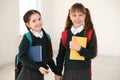 Portrait of cute girls in school uniform with backpacks and books Royalty Free Stock Photo