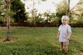 Portrait of Cute Handsome Blond Little Kid Boy in Colorful Striped Button Down Shirt Walking Outside in the Grass Watching the Sun Royalty Free Stock Photo