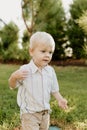 Portrait of Cute Handsome Blond Little Kid Boy in Colorful Striped Button Down Shirt Walking Outside in the Grass Watching the Sun Royalty Free Stock Photo