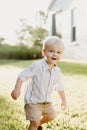 Portrait of Cute Handsome Blond Little Kid Boy in Colorful Striped Button Down Shirt Walking Outside in the Grass Watching the Sun Royalty Free Stock Photo