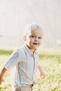 Portrait of Cute Handsome Blond Little Kid Boy in Colorful Striped Button Down Shirt Walking Outside in the Grass Watching the Sun Royalty Free Stock Photo