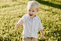 Portrait of Cute Handsome Blond Little Kid Boy in Colorful Striped Button Down Shirt Walking Outside in the Grass Watching the Sun Royalty Free Stock Photo