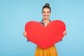 Portrait of cute happy attractive woman with amiable smile holding big red paper heart, expressing love affection