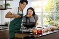 Portrait of cute happy couple in apron in cheeful action tasting and smelling breakfast of macaroni table decorated with