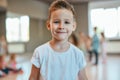 Portrait of a cute and happy little boy in white t-shirt looking at camera with smile while standing in the dance studio Royalty Free Stock Photo