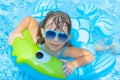 Portrait of cute happy little girl having fun in swimming pool, floating in blue refreshing water wit rubber ring, active summer v Royalty Free Stock Photo