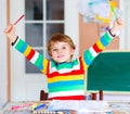 Portrait of cute happy school kid boy at home making homework. Little child writing with colorful pencils, indoors Royalty Free Stock Photo