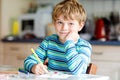 Portrait of cute healthy happy school kid boy at home making homework. Little child writing with colorful pencils Royalty Free Stock Photo