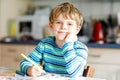 Portrait of cute healthy happy school kid boy at home making homework. Little child writing with colorful pencils Royalty Free Stock Photo