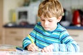 Portrait of cute healthy happy school kid boy at home making homework. Little child writing with colorful pencils Royalty Free Stock Photo