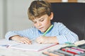 Portrait of cute healthy happy school kid boy at home making homework. Little child writing with colorful pencils Royalty Free Stock Photo