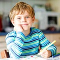 Portrait of cute healthy happy school kid boy at home making homework. Little child writing with colorful pencils Royalty Free Stock Photo