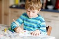 Portrait of cute healthy happy school kid boy at home making homework. Little child writing with colorful pencils Royalty Free Stock Photo