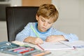 Portrait of cute healthy happy school kid boy at home making homework. Little child writing with colorful pencils Royalty Free Stock Photo