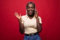 Portrait of cute joyful woman with trendy hairstyle talking on mobile phone and touching her brown locks isolated over red Royalty Free Stock Photo