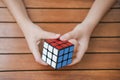 Portrait of cute kid boy holding Rubik`s cube and playing with it at the desk. Rubik`s cube in child`s hands. Banner.