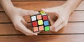 Portrait of cute kid boy holding Rubik`s cube and playing with it at the desk. Rubik`s cube in child`s hands. Banner. Royalty Free Stock Photo