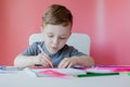 Portrait of cute kid boy at home making homework. Little concentrated child writing with colorful pencil, indoors. Elementary Royalty Free Stock Photo