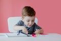 Portrait of cute kid boy at home making homework. Little concentrated child writing with colorful pencil, indoors. Elementary