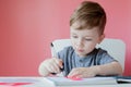 Portrait of cute kid boy at home making homework. Little concentrated child writing with colorful pencil, indoors. Elementary Royalty Free Stock Photo