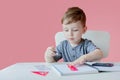 Portrait of cute kid boy at home making homework. Little concentrated child writing with colorful pencil, indoors. Elementary