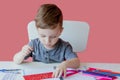 Portrait of cute kid boy at home making homework. Little concentrated child writing with colorful pencil, indoors. Elementary Royalty Free Stock Photo