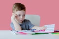 Portrait of cute kid boy at home making homework. Little concentrated child writing with colorful pencil, indoors. Elementary