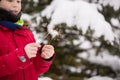 Portrait of cute kid boy looking at sparkler at the Christmas tree outdoors. Child having fun in the winter park. Lifestyle and Royalty Free Stock Photo