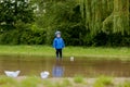 Portrait of cute kid boy playing with handmade ship. kindergarten boy sailing a toy boat by the waters` edge in the park