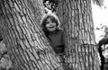 Portrait of cute kid boy sitting on the big old tree on summer day. Child climbing a tree. Little boy sitting on tree Royalty Free Stock Photo