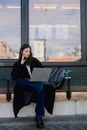 Portrait of cute Korean girl in cafe near window and networking, looking at laptop and drinking coffee. Student having cappuccino Royalty Free Stock Photo