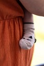 A portrait of the cute leg and foot of a baby wearing a cosy sock pressed safely against the caring mother who is carying the