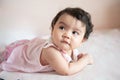 Portrait of a cute little Asian baby girl wear pink dress lying on bed, looking out, baby expression concept Royalty Free Stock Photo