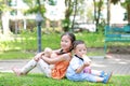 Portrait of cute little Asian sister and her younger brother sit back and lean back together in the green garden. Child girl Royalty Free Stock Photo