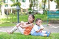 Portrait of cute little Asian sister and her younger brother sit back and lean back together in the green garden. Child girl Royalty Free Stock Photo