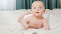 Portrait of cute little baby boy with blue eyes lying on bed and looking in camera. Royalty Free Stock Photo