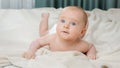 Portrait of cute little baby boy with blue eyes lying on white blanket in bedroom Royalty Free Stock Photo