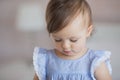 Portrait of a cute little baby girl in a blue dress looks down Royalty Free Stock Photo