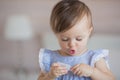 Portrait of a cute little baby girl in a blue dress plays with a plastic thing