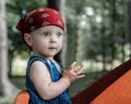 A portrait of a nice little baby girl with blue eyes, wearing a red bandana and a blue jeans dress. Royalty Free Stock Photo