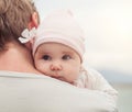 Portrait of cute little baby girl with flower on father shoulder outdoors, parental care and safety concept